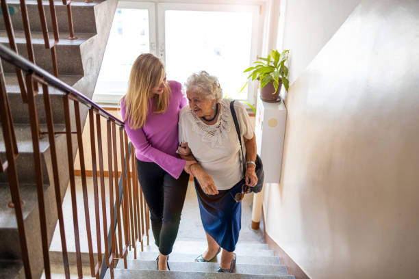 Caregiver helping senior woman climb staircase Service à la personne à Paris 6