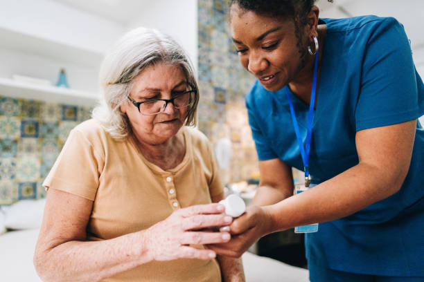 Nurse explaining to senior woman how to take her medicine at home soins infirmiers à domicile